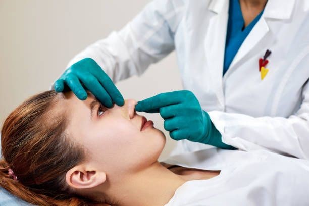 A health and aesthetic beauty professional who is evaluating a rhinoplasty job that has been performed on a satisfied patient.